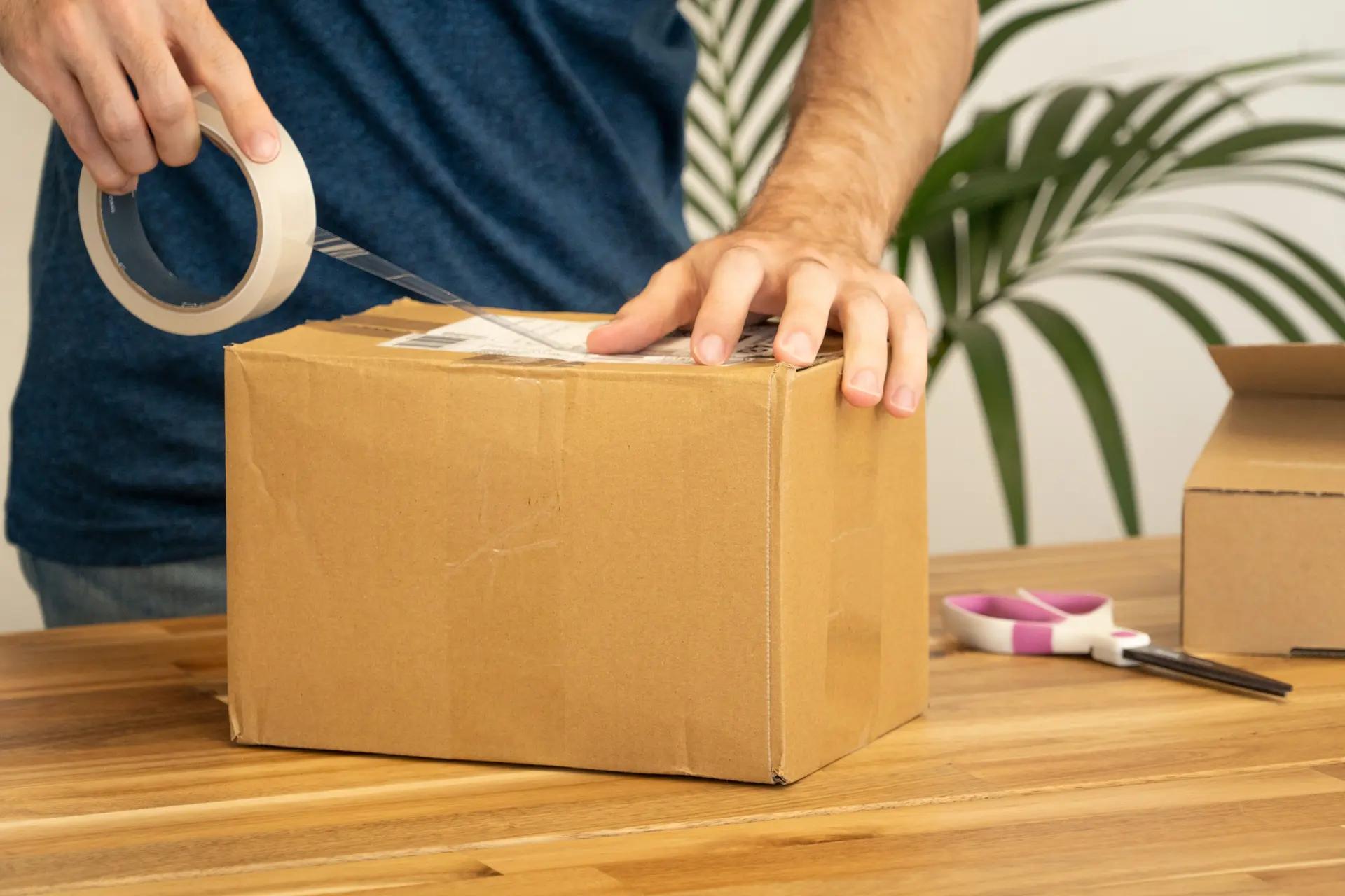 Hands sealing a cardboard parcel ready for delivery